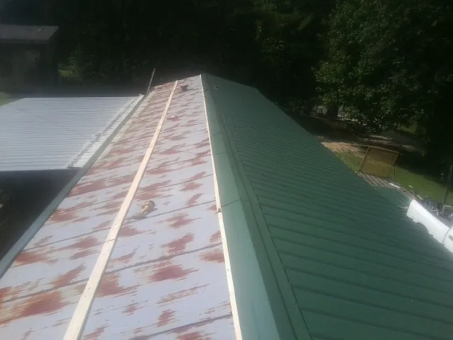 Old rusted panels beside newly installed green metal roofing — Wind Damage Roof Repair by Roofing Brothers in Duncan