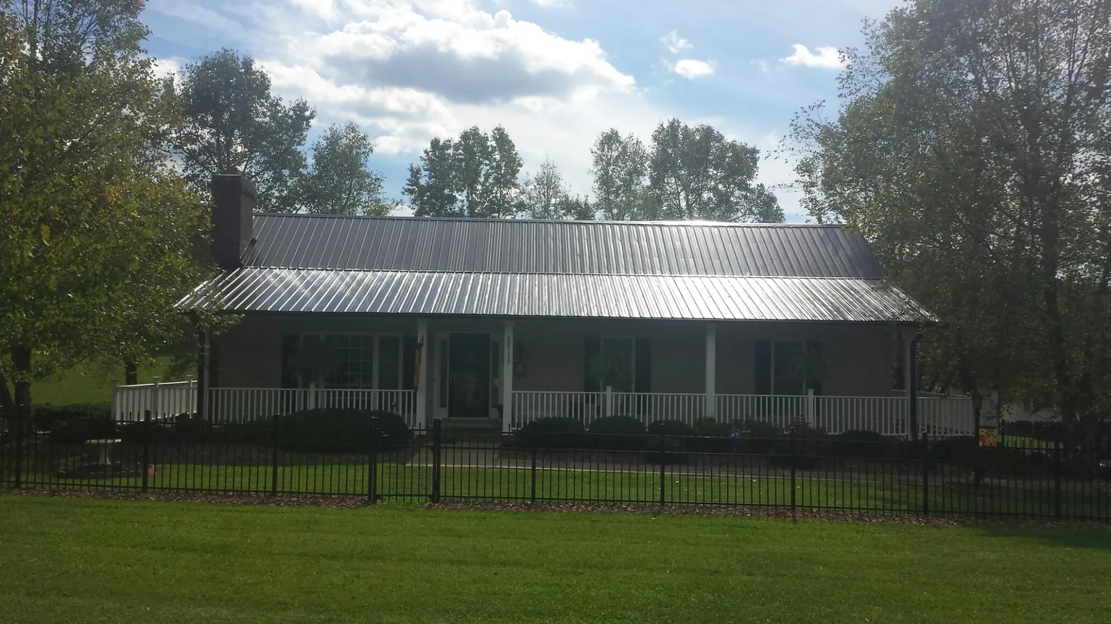 Gray metal roof on a brick ranch with a full width front porch — Gutter Guard Installation work by our crew in Duncan